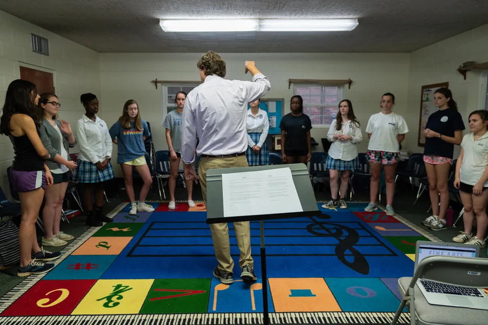 Music teacher conducting a group of older students at ACA