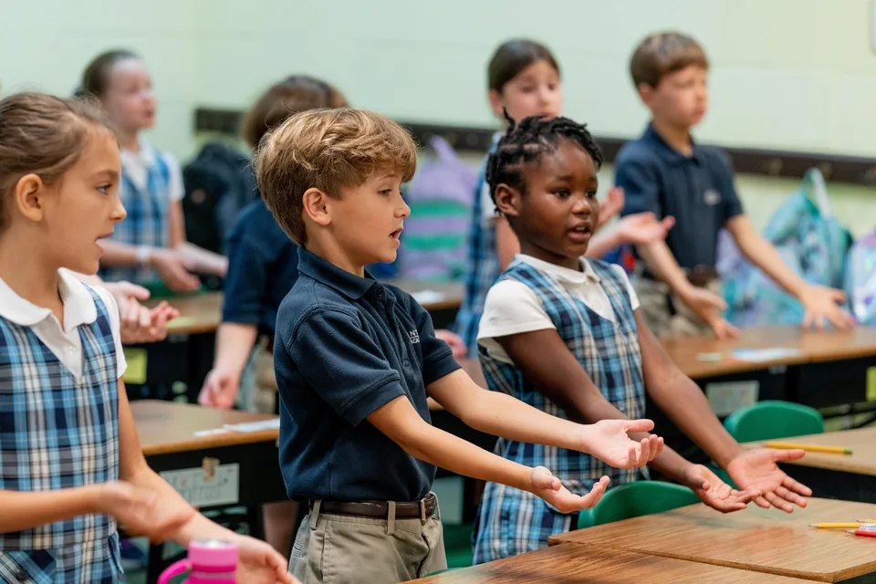 Children standing and gesturing during a classroom activity at ACA