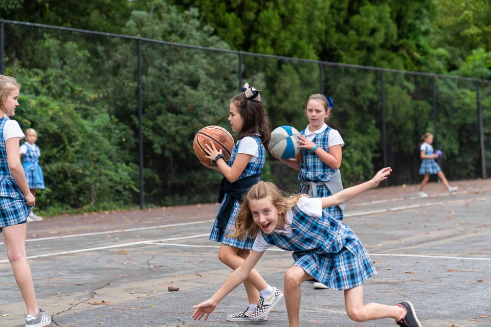 Children playing outdoors with basketballs at ACA